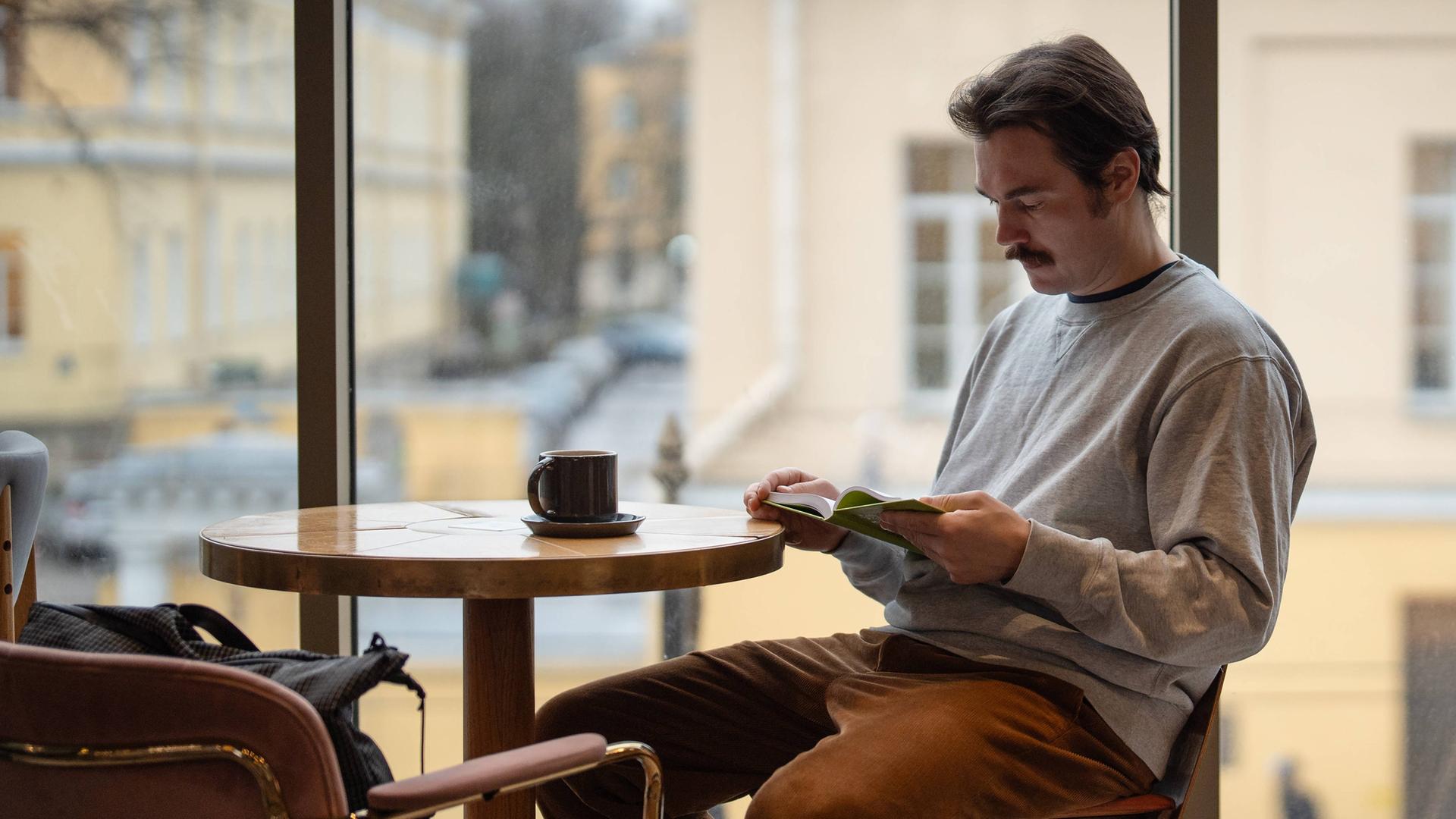 Ein Mann sitzt in einem Café und liest nachdenklich ein Buch Ein Mann sitzt in einem Café und liest nachdenklich ein Buch