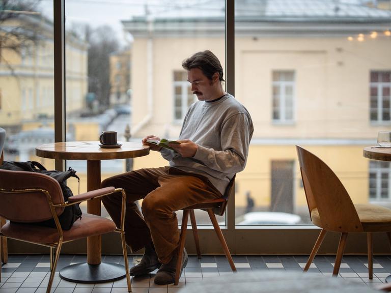 Ein Mann sitzt in einem Café und liest nachdenklich ein Buch Ein Mann sitzt in einem Café und liest nachdenklich ein Buch