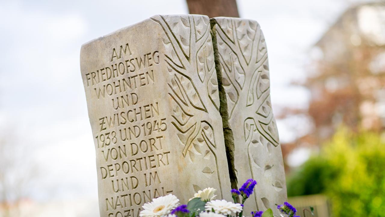 Ein Blumenkranz liegt bei einer Gedenkveranstaltung vor einer Gedenkstele für die in der NS-Zeit deportierten Sinti und Roma aus Oldenburg. Auf der Gedenkstele sind Namen der deportierten Menschen zu lesen. 
