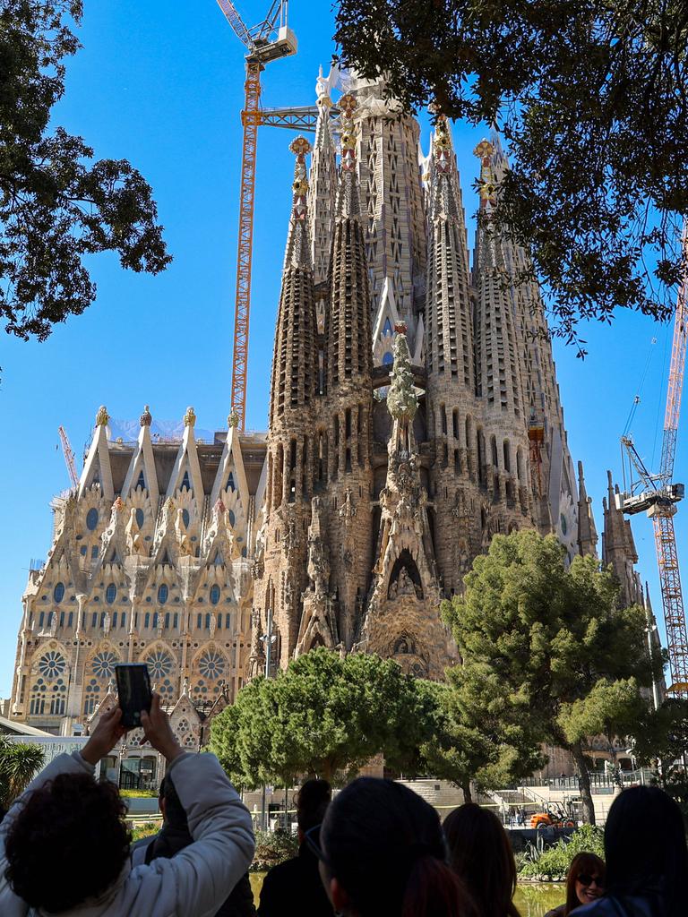 Blick auf die weltberühmte Basilika 'Sagrada Familia' von Gaudi in Barcelona, eine Touristengruppe steht in der Nähe und macht Fotos davon.