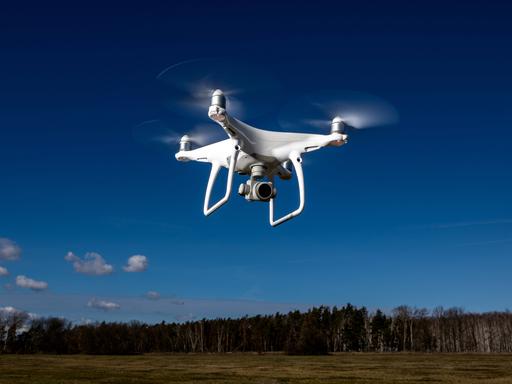 Ein Symbolfoto zeigt eien Kameradrohne Modell DJI Phantom, die vor blauem Himmel fliegt.