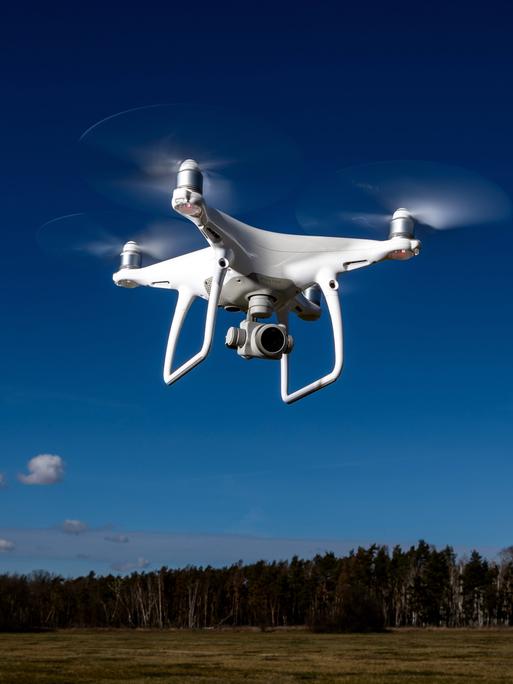 Ein Symbolfoto zeigt eien Kameradrohne Modell DJI Phantom, die vor blauem Himmel fliegt.