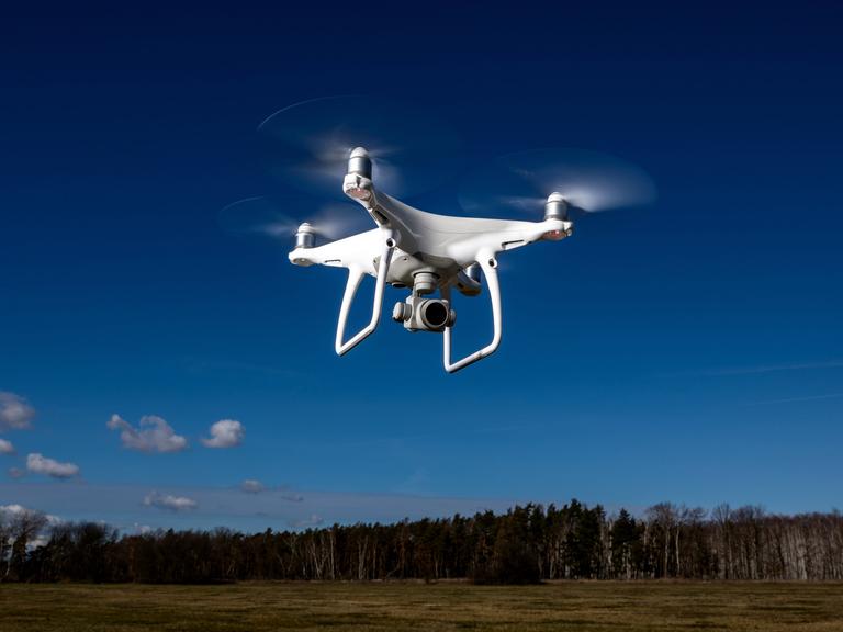 Ein Symbolfoto zeigt eien Kameradrohne Modell DJI Phantom, die vor blauem Himmel fliegt.