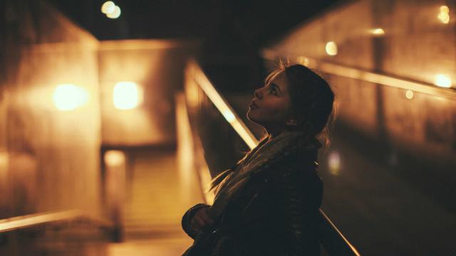 Eine junge Frau blickt bei Nacht nachdenklich gen Himmel.