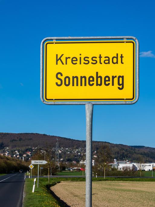 Gelbes Ortsschild von Sonneberg in Thüringen vor blauem Himmel