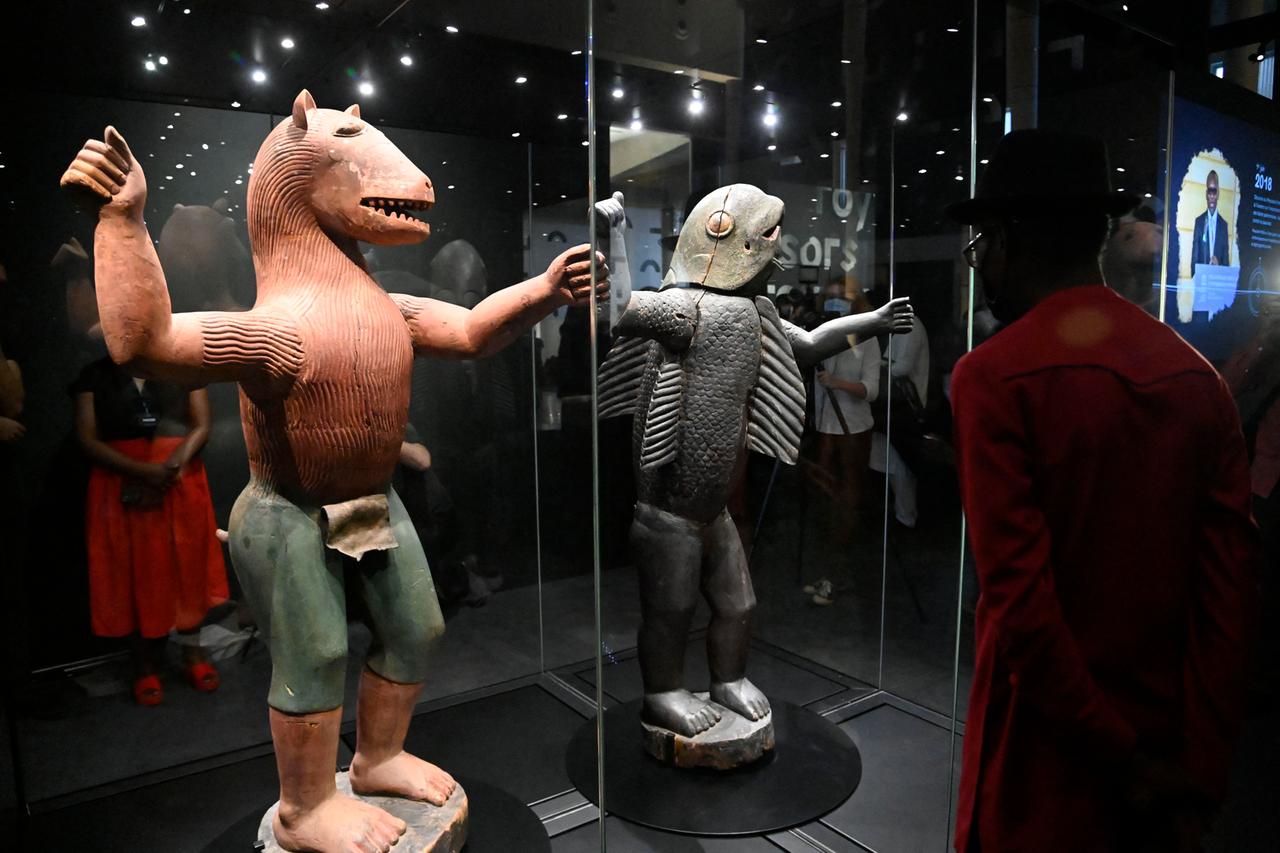 Besucher betrachten zwei Statuen, die Mischwesen aus Mensch und Tier darstellen und die beiden letzten Könige des Reiches Dahomey zeigen.