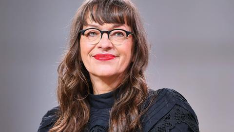 Ein weiße Frau mit Brille und langen braunen Haaren blickt in die Kamera.