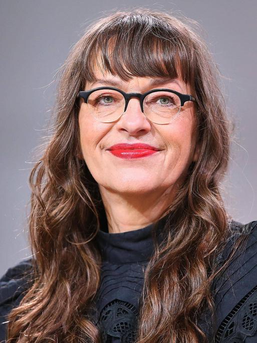 Ein weiße Frau mit Brille und langen braunen Haaren blickt in die Kamera. Ein weiße Frau mit Brille und langen braunen Haaren blickt in die Kamera.