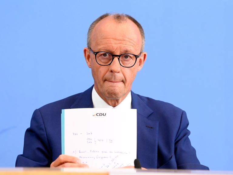 Foto zeigt Friedrich Merz bei der Bundespressekonferenz zu den Konsequenzen aus Solingen im Haus der Bundespressekonferenz in Berlin. Dabei hält er einen Notizettel mit dem Logo der CDU in den Händen.