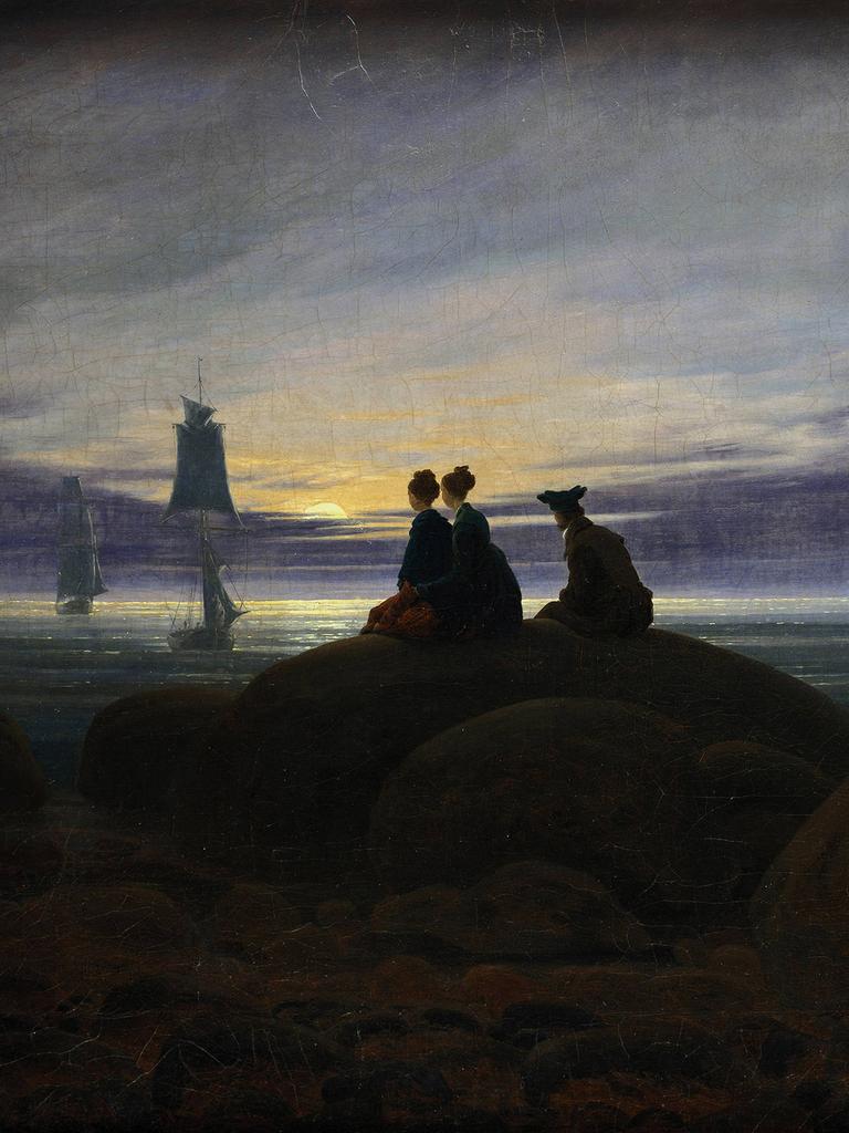 Digitale Reproduktion des Gemäldes Mondaufgang am Meer" (1822) von Caspar David Friedrich (1774 -1840). Zu sehen sind zwei Frauen und ein Mann, die auf einem Felsen im Mondschein sitzend auf in der Ostsee ankernde Segelschiffe schauen. 