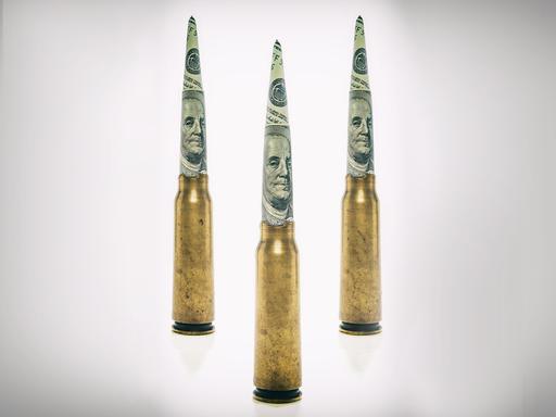 Patronenhülsen auf deren Spitze zu Zylindern gerollte Dollarnoten stecken Patronenhülsen auf deren Spitze zu Zylindern gerollte Dollarnoten stecken