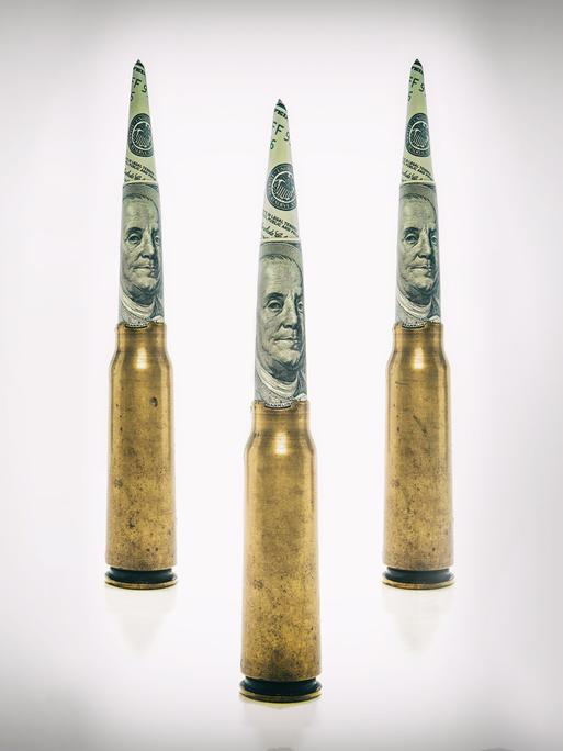 Patronenhülsen auf deren Spitze zu Zylindern gerollte Dollarnoten stecken Patronenhülsen auf deren Spitze zu Zylindern gerollte Dollarnoten stecken