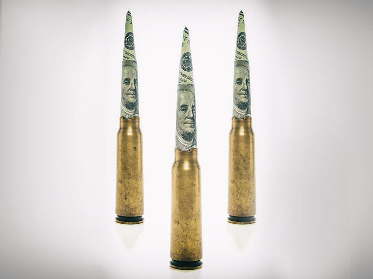 Patronenhülsen auf deren Spitze zu Zylindern gerollte Dollarnoten stecken