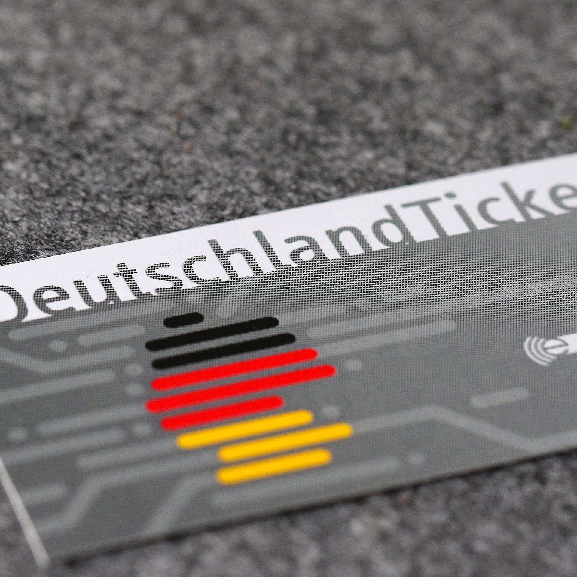 Eine Abokarte des Deutschlandtickets für den öffentlichen Nahverkehr liegt auf einem grauen Untergrund