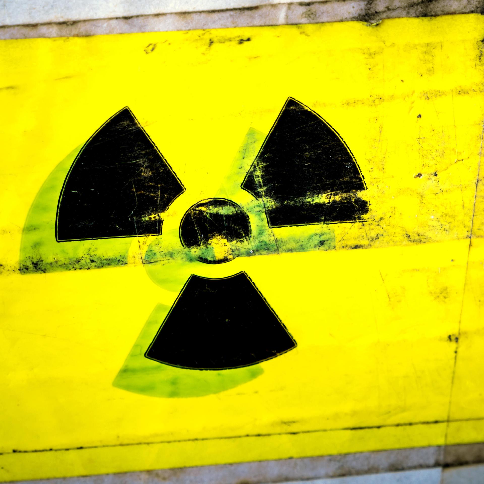 Zu sehen ist das schwarze Symbol für Radioaktivität auf gelbem Grund. Hier: ein Warnschild für radioaktive Stoffe auf einem Paket.