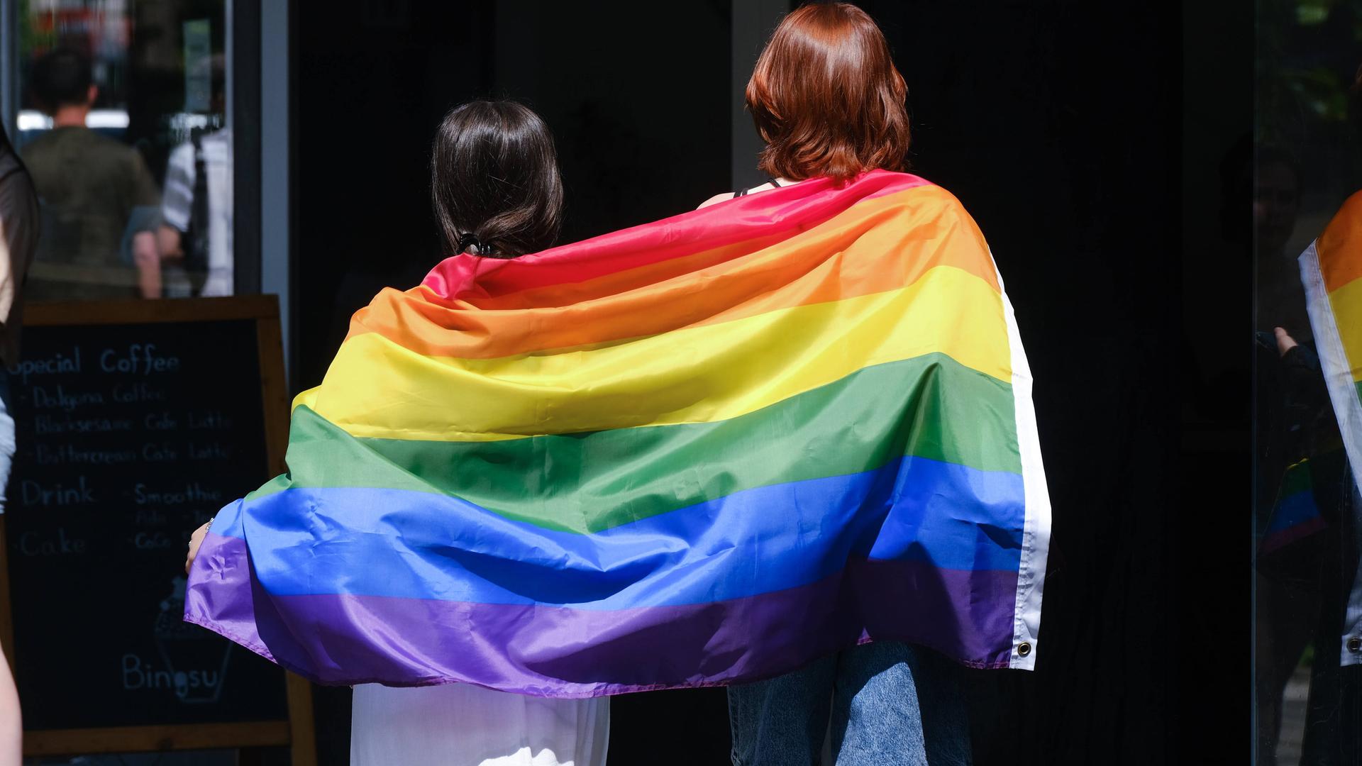 Zwei Frauen tragen auf einem CSD eine Regen-Bogen-Fahne. Zwei Frauen tragen auf einem CSD eine Regen-Bogen-Fahne.