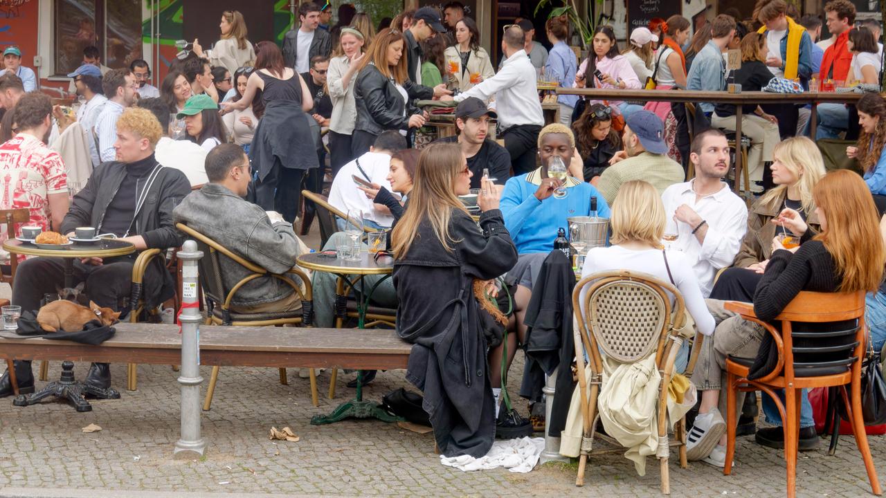 Viele junge Leute sitzen auf der Terrasse eines Cafés.