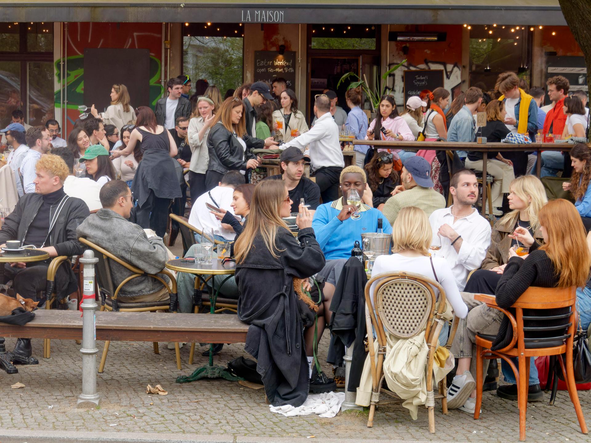 Viele junge Leute sitzen auf der Terrasse eines Cafés.