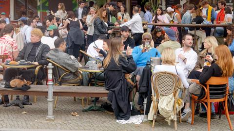 Viele junge Leute sitzen auf der Terrasse eines Cafés.