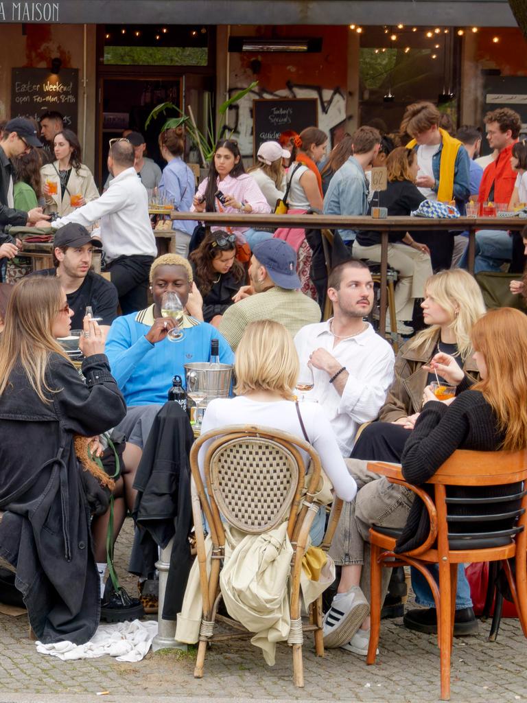 Viele junge Leute sitzen auf der Terrasse eines Cafés.