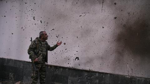 Ein Mann zeigt auf eine durch Grananten beschädigte Wand in der armenischen Stadt Jermuk am 15. September 2022 Ein Mann zeigt auf eine durch Grananten beschädigte Wand in der armenischen Stadt Jermuk am 15. September 2022