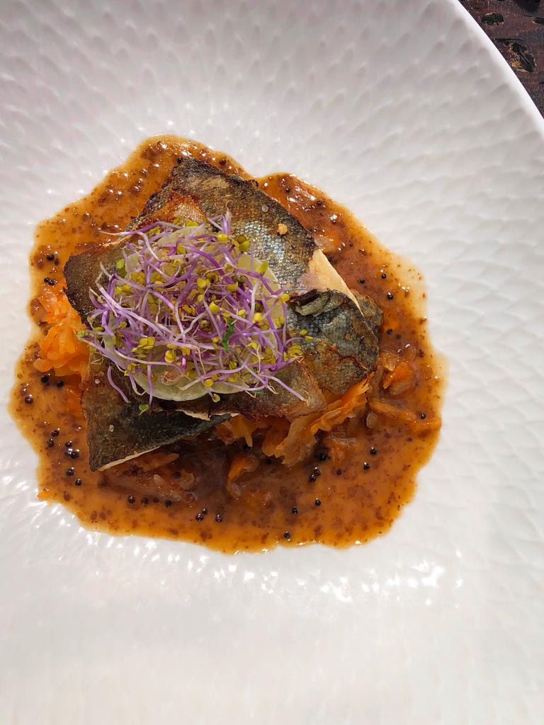 Gebratene Forellenfilets und bayrisches Kim Chi mit Teigtaschen und Sesam sind in zwei weißen Tellern angerichtet