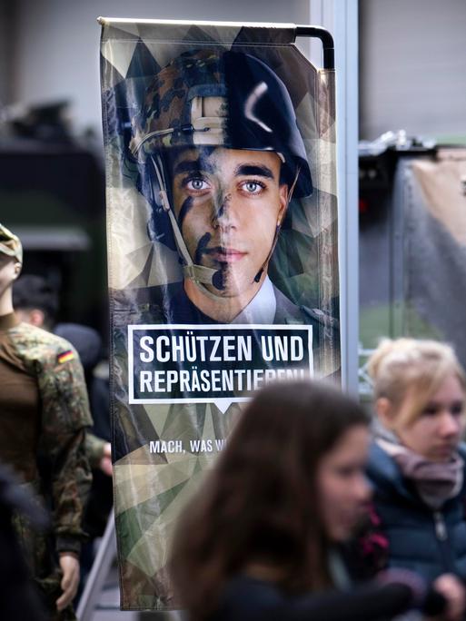 Junge Besucher am Stand der Bundeswehr mit einem Werbeplakat unter dem Slogan "Schützen und Repräsentieren" mit dem Bild eines jungen Menschen in Uniform und Helm, auf der Messe der Internationalen Grünen Woche in Berlin, 2026.
