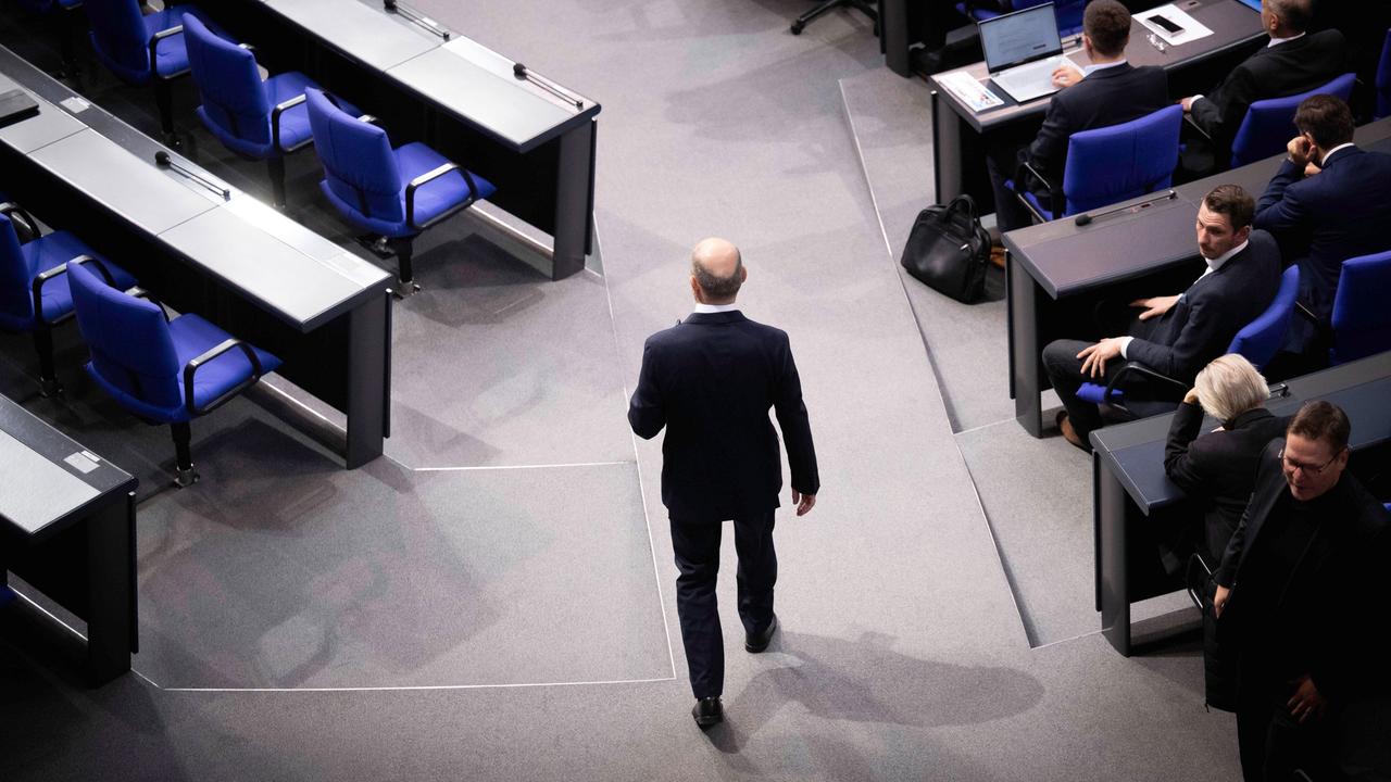 Olaf Scholz während der Debatte bei einer Sitzung des Deutschen Bundestages. Man sieht ihn von hinten durch die Reihen laufen. 