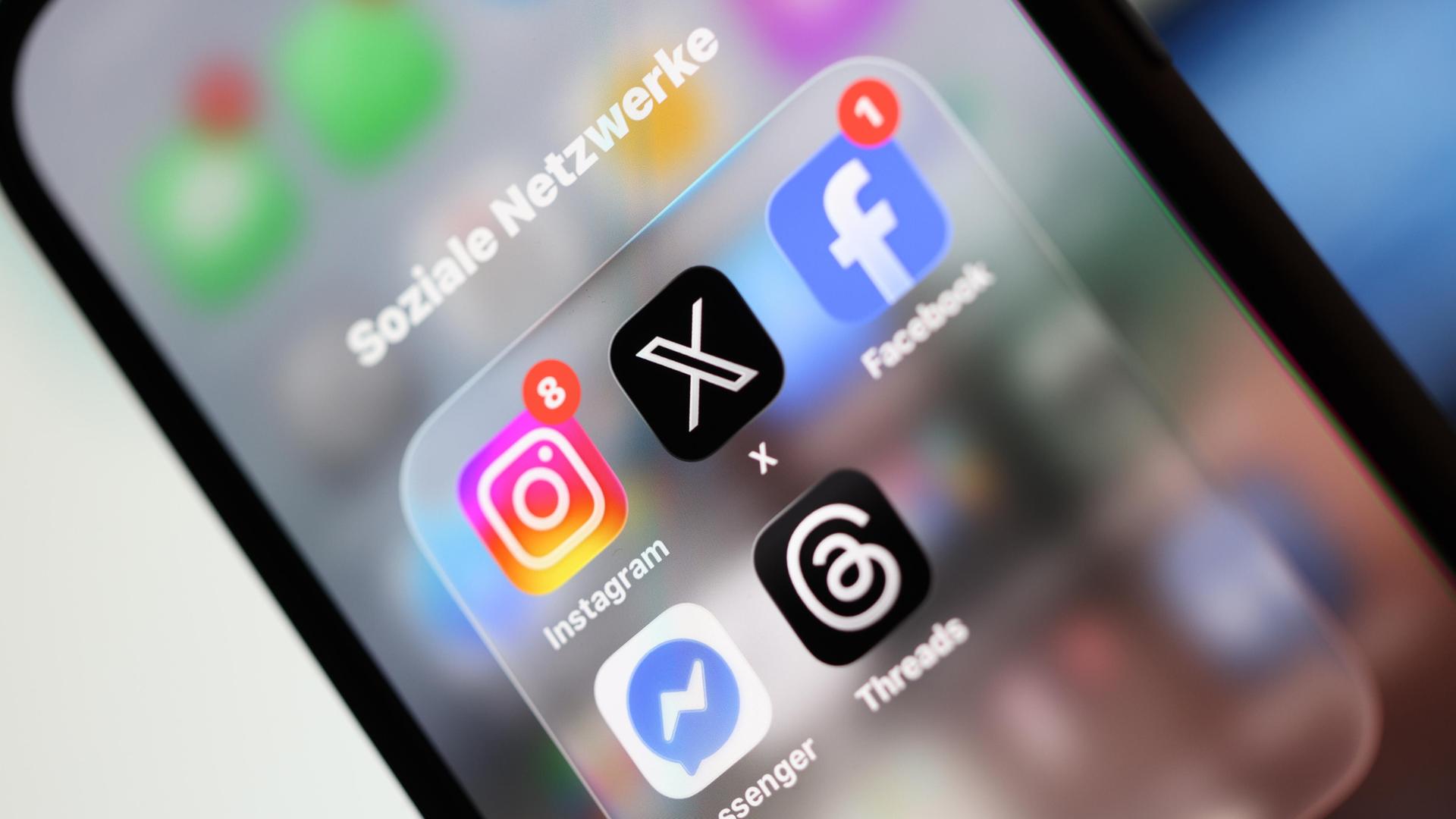 Ein Smartphone-Display zeigt Symbole verschiedener Apps sozialer Netzwerke, darunter X, Facebook, Instagram, Threads und Messenger.