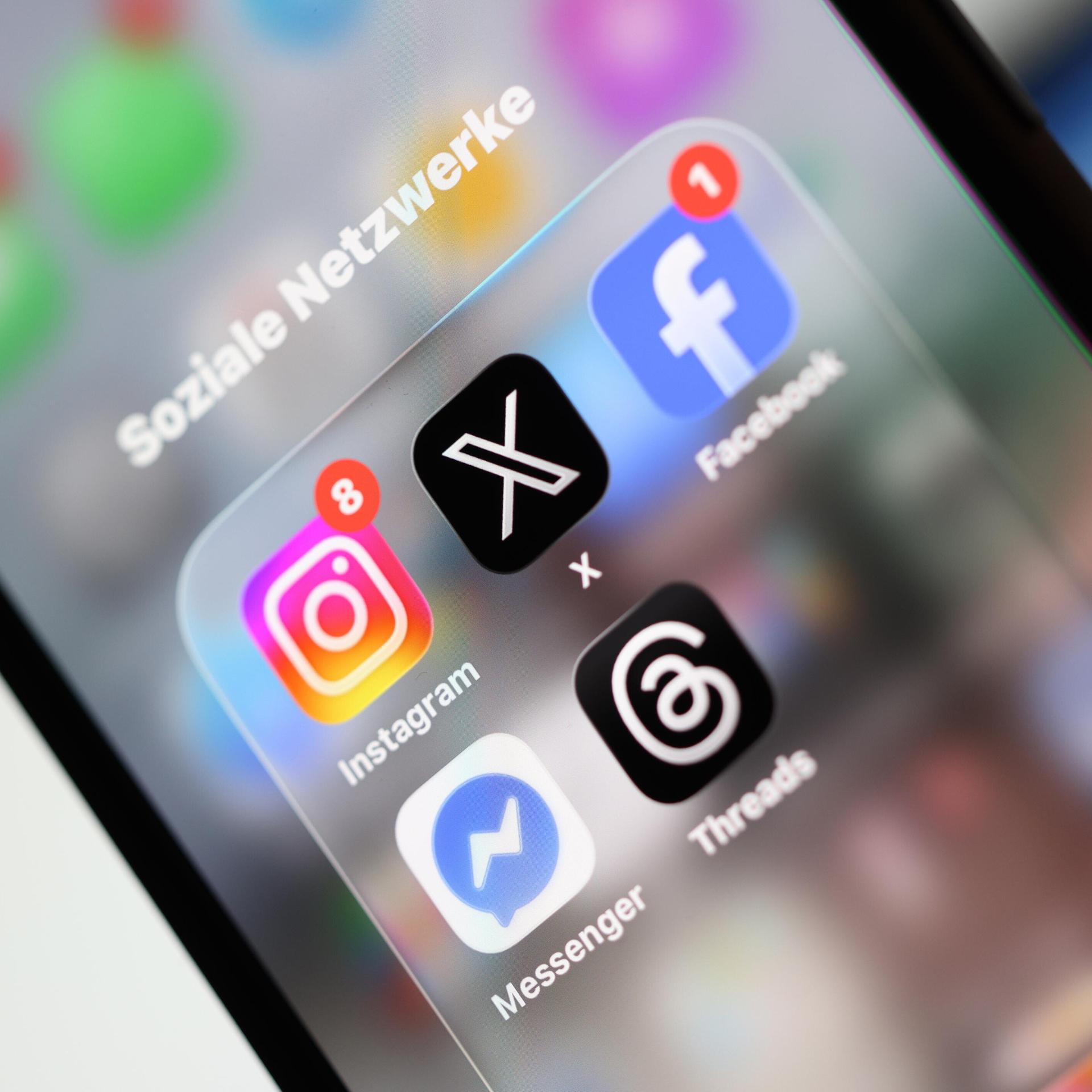 Ein Smartphone-Display zeigt Symbole verschiedener Apps sozialer Netzwerke, darunter X, Facebook, Instagram, Threads und Messenger.