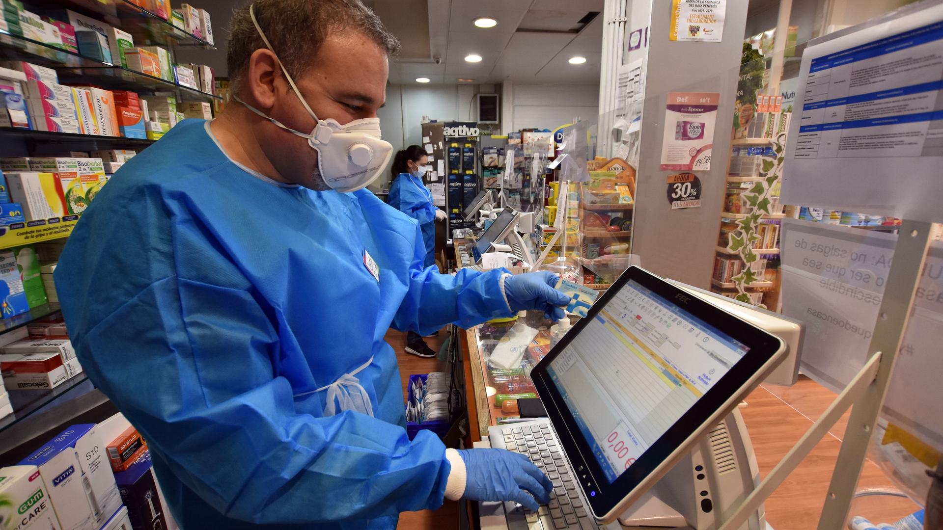 Ein Apotheker im spanischen Vendrell überprüft digital die Gesundheitskarte eines Kunden. 