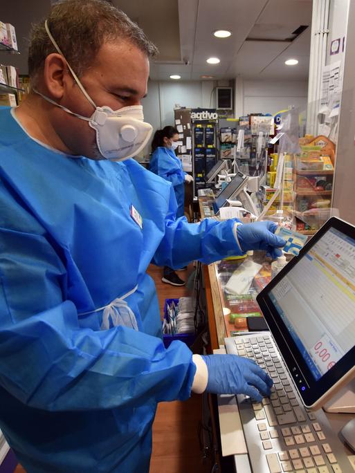 Ein Apotheker im spanischen Vendrell überprüft digital die Gesundheitskarte eines Kunden. 