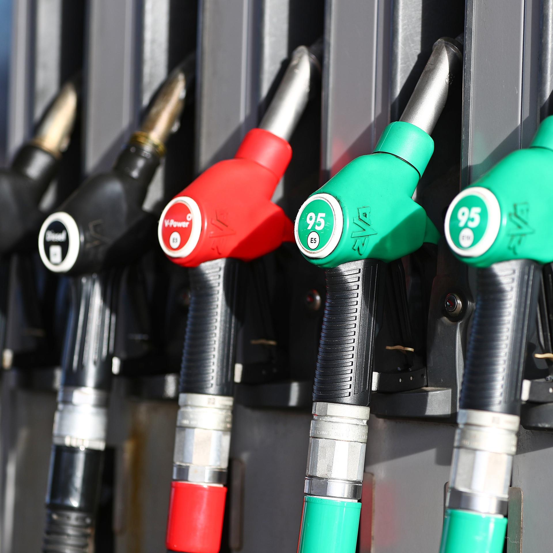 Das Bild zeigt mehrere Tankschläuche an einer Zapfsäule. Sie hängen nebeneinander in ihren Halterungen, meist farblich gekennzeichnet – etwa grün für Benzin. 