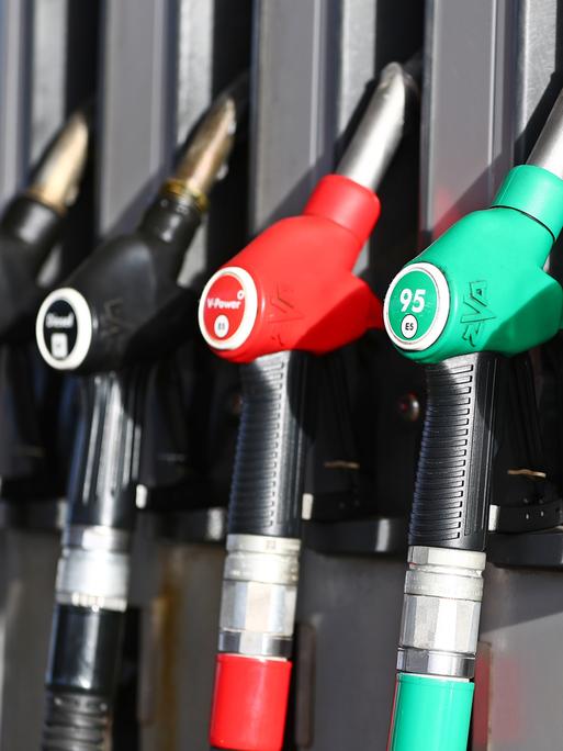 Das Bild zeigt mehrere Tankschläuche an einer Zapfsäule. Sie hängen nebeneinander in ihren Halterungen, meist farblich gekennzeichnet – etwa grün für Benzin. 