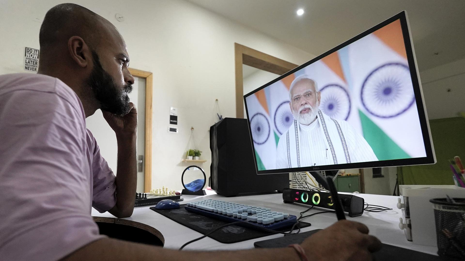 Unternehmer in Indien vor einem Computer mit einem Deepfake-Video, das vorgeblich den indischen Premier Narendra Modi zeigt.