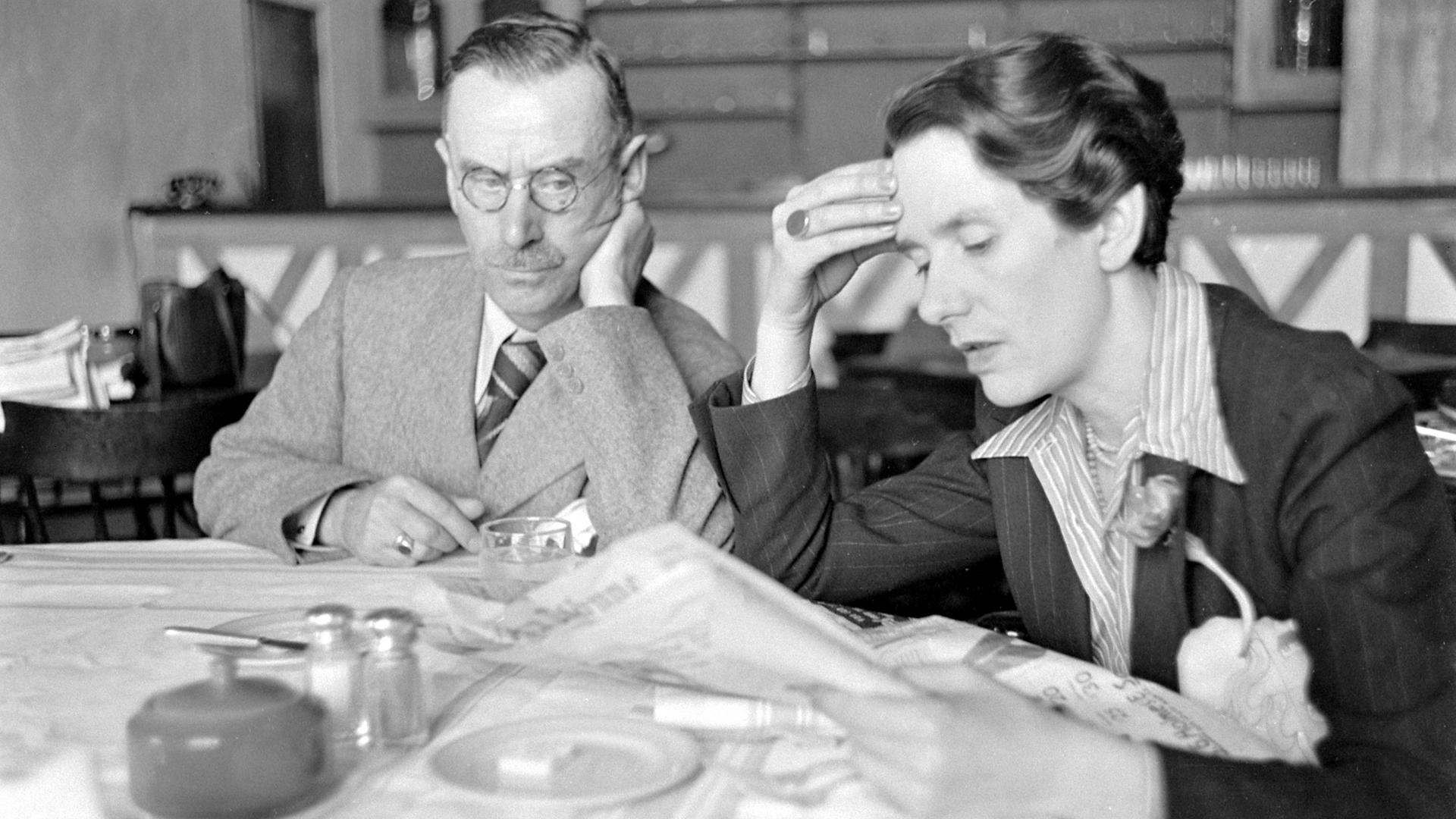 Erika Mann und ihr Vater Thomas Mann sitzen gemeinsam an einem Tisch in Tulsa, Oklahoma. Erika Mann liest Zeitung. USA 1939.