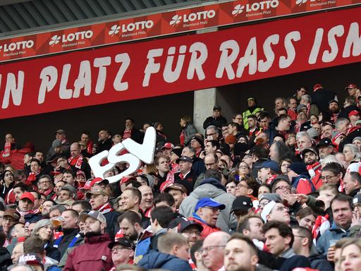 Über Mainzer Fans hängt das Spruchband in weißer Schrift auf rotem Grund.