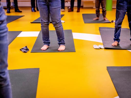 Kinder stehen barfuß im Klassenraum auf Gymnastikmatten