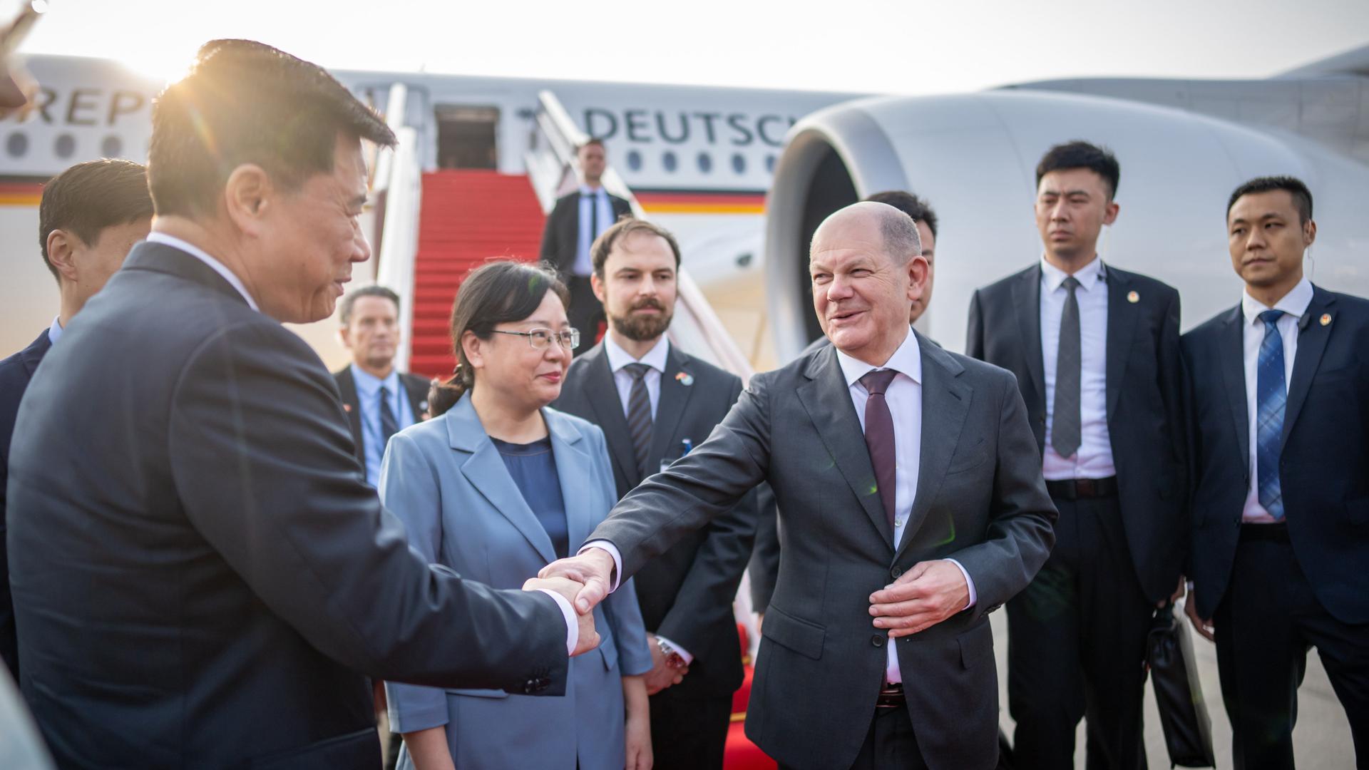 Bundeskanzler Olaf Scholz (SPD), steigt am Flughafen von Chongqing in China aus dem Flugzeug und wird von Zhang Guozhi, Vizebürgermeisterin der Stadt Chongqing begrüßt.