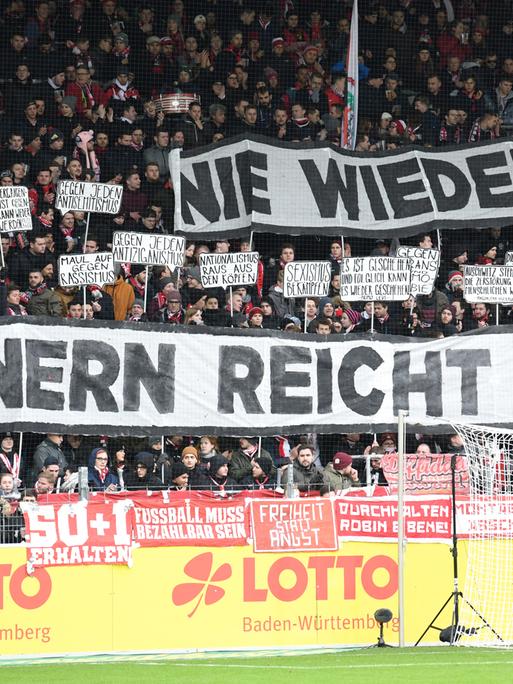 Zuschauer halten beim Fußball-Bundesligaspiel SC Freiburg gegen 1899 Hoffenheimbeim im Freiburger Schwarzwaldstadion Plakate mit der Aufschrift "Nie wieder! Erinnern reicht nicht"  in die Höhe.