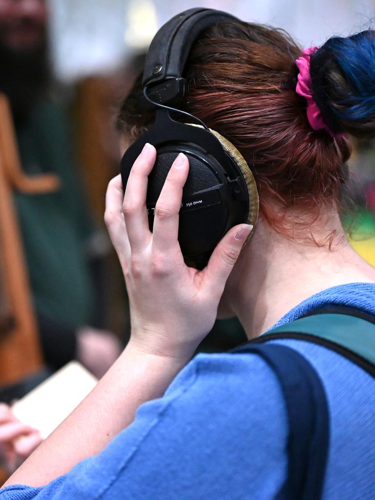 Eine Frau lauscht mit großen Kopfhörern auf dem Kopf einem Hörbuch auf der Leipziger Buchmesse. Man sieht sie von der Seite. 