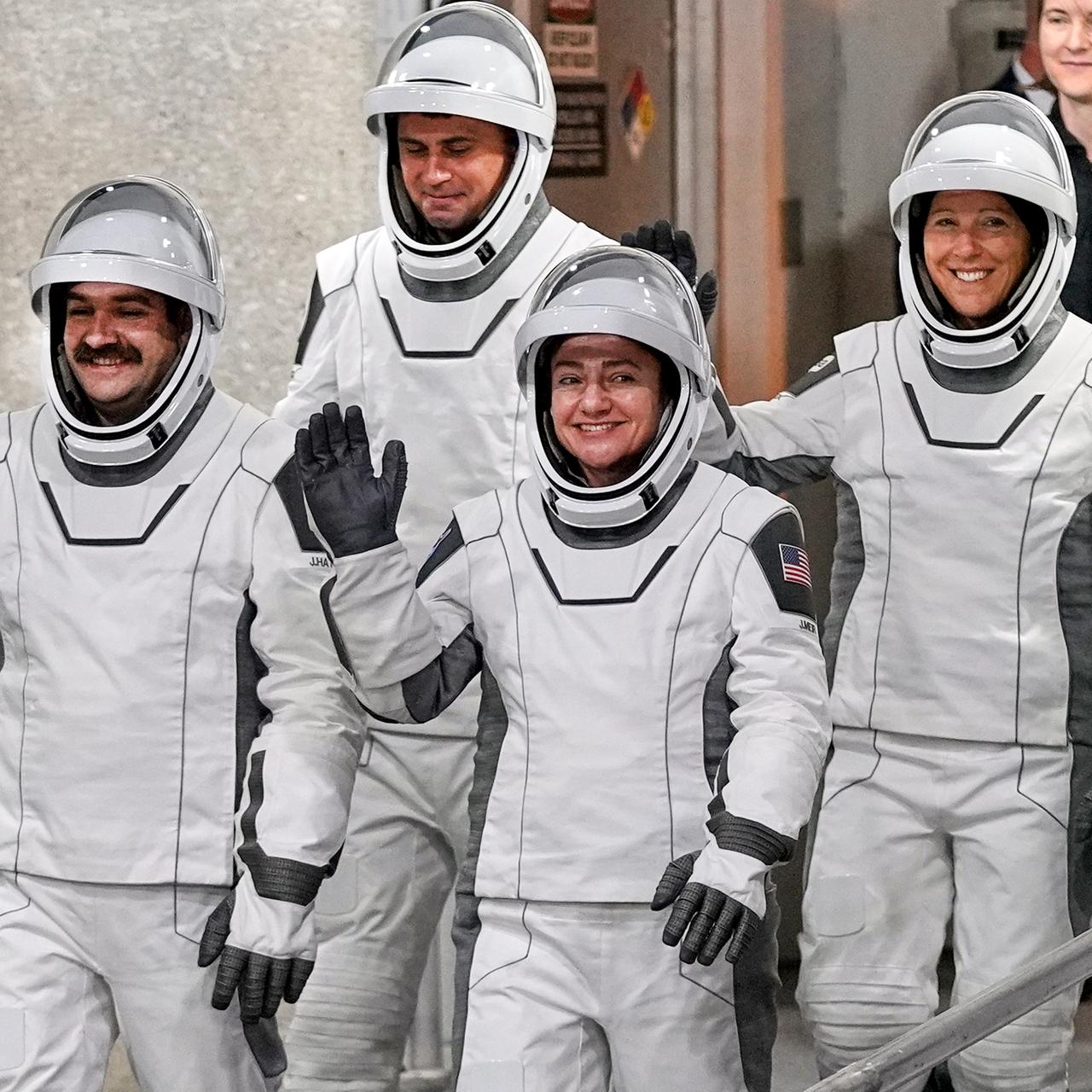 Das Bild zeigt vier Raumfahrerinen und Raumfahrer in ihren Schutzanzügen und mit Helm vor dem Abheben ihrer Rakete.