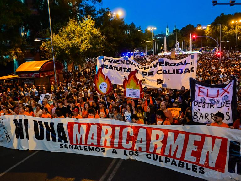 Demonstrierende ziehen in Madrid mit Bannern durch die Straßen, vorweg tragen sie ein großes Banner mit der Aufschrift "Ni una Maricarmen más" ("Keine weitere Maricarmen").

