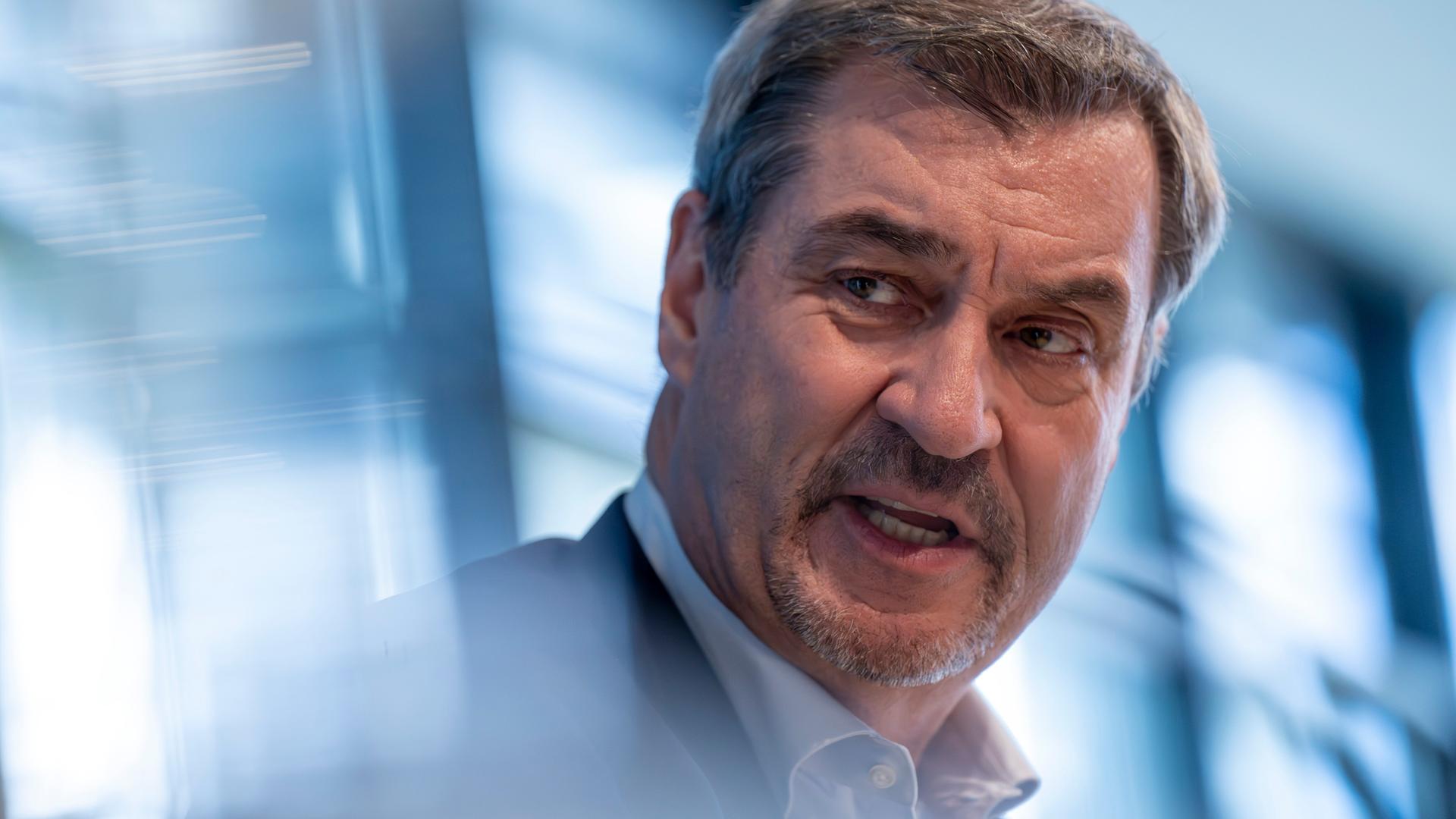 Porträtaufnahme vor bläulich verschwommenen Hintergrund von Markus Söder. Der bayerische Ministerpräsident redet ernst Porträtaufnahme vor bläulich verschwommenen Hintergrund von Markus Söder. Der bayerische Ministerpräsident redet ernst