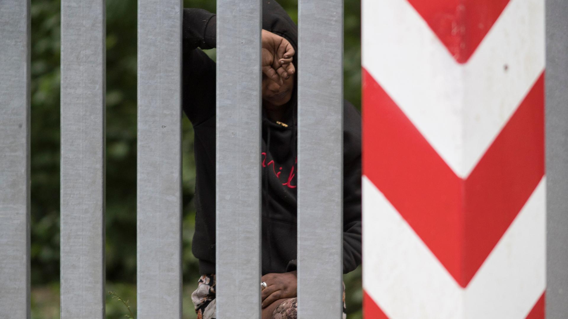 Das Bild zeigt eine äthiopische Frau hinter dem Grenzzaun zwischen Belarus und Polen.