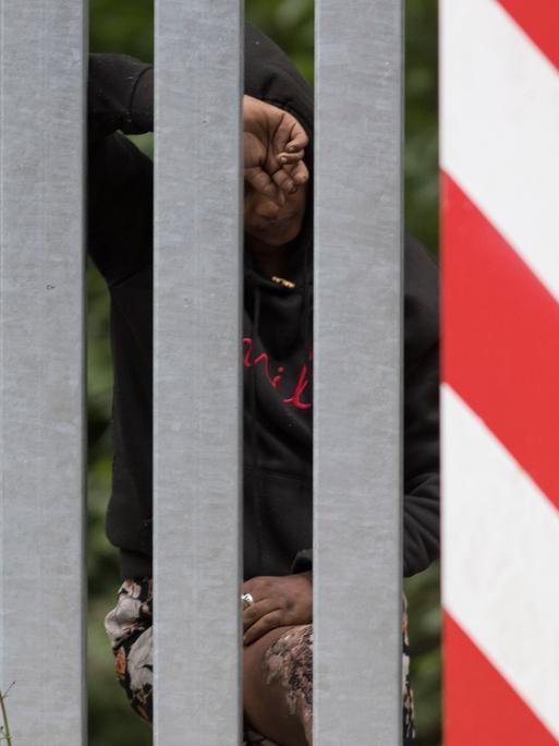 Das Bild zeigt eine äthiopische Frau hinter dem Grenzzaun zwischen Belarus und Polen.