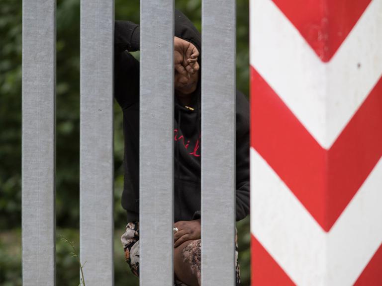 Das Bild zeigt eine äthiopische Frau hinter dem Grenzzaun zwischen Belarus und Polen.