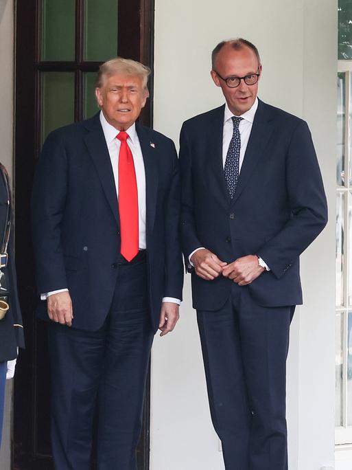 US-Präsident Donald Trump und Bundeskanzler Friedrich Merz nebeneinander vor dem Weißen Haus, neben ihnen sind die amerikanische und die deutsche Flagge gehisst.