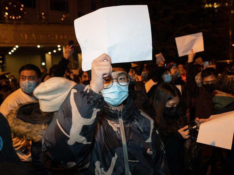 Ein Protestierender in Peking äußert seinen Unmut ohne Worte. Er hält ein weißes Blatt Papier in die Höhe.