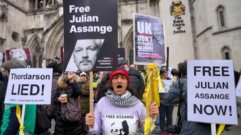 Eine Frau steht vor dem High Court in London und hält ein Schild mit der Aufschrift "Free Assange".